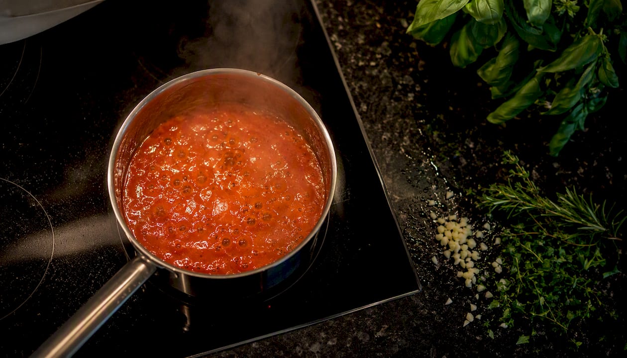Simmering tomato-piquillo pepper sauce in saucepan