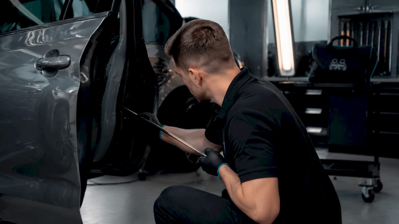 Dent repair technician using PDR rod inside garage