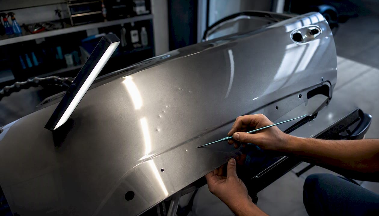 Close-up of car dents inspected under LED light