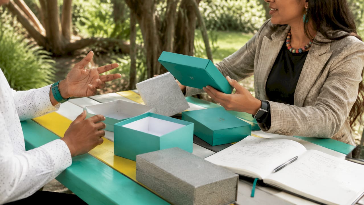 Hands comparing different branded gift boxes