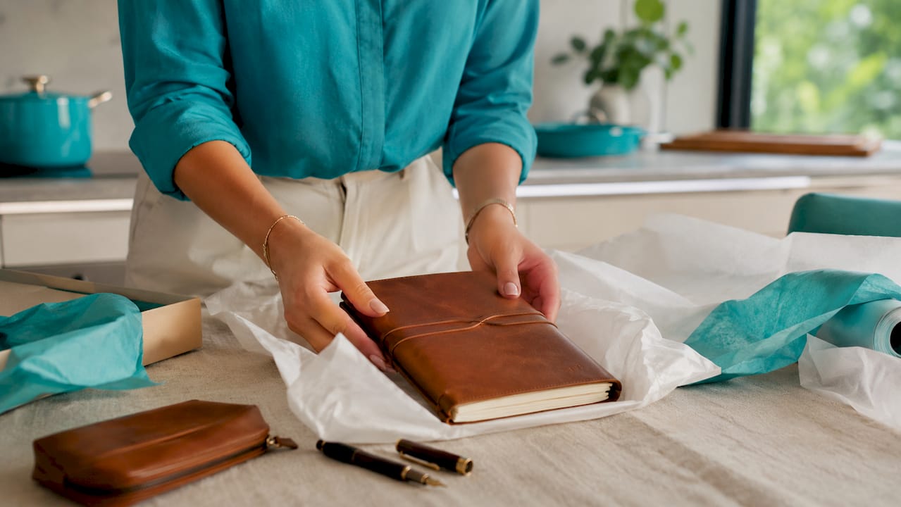 Hands arranging hero item in gift box flat lay
