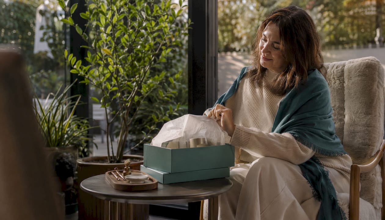 Woman opening luxury candle gift set at home
