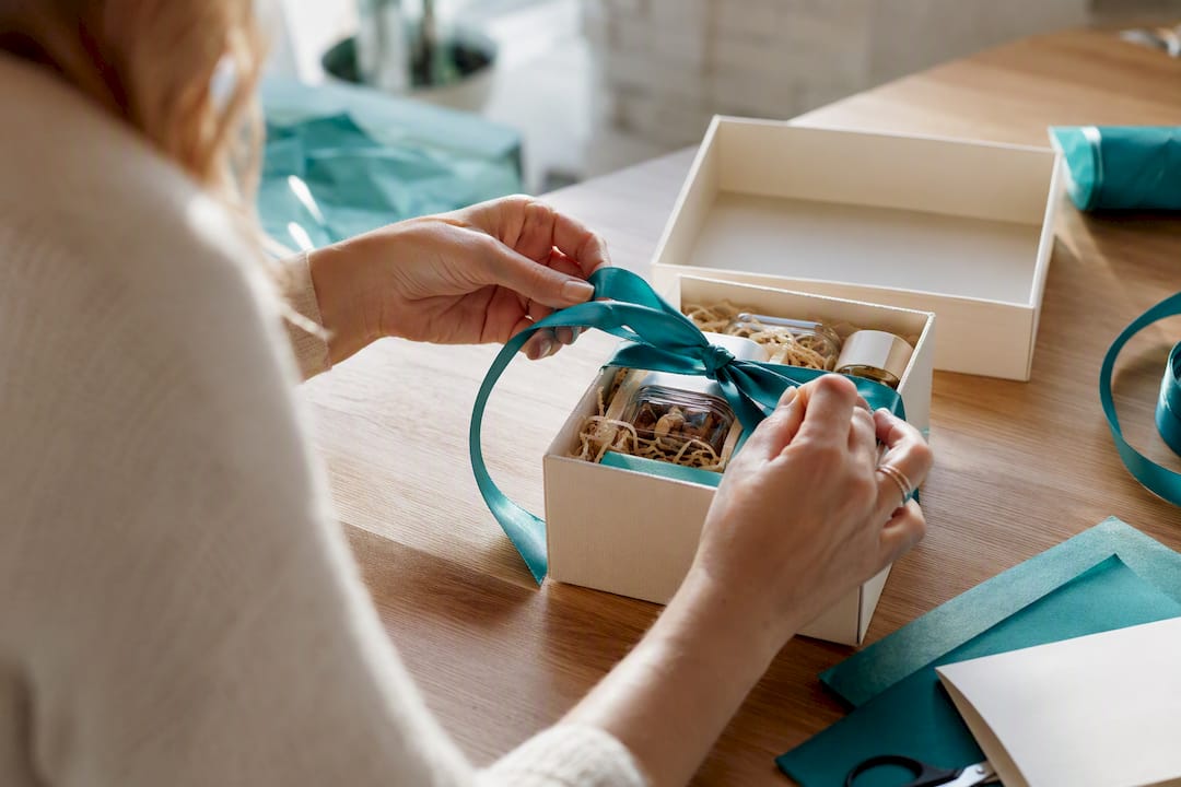 Hands wrapping ribbon on gift box