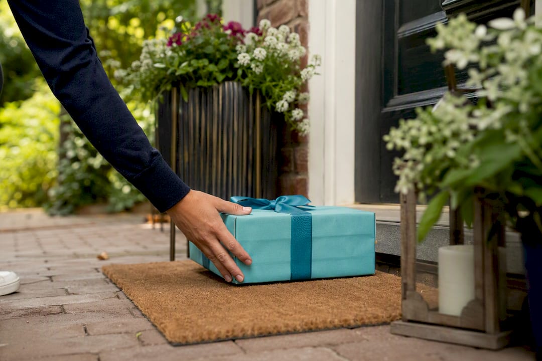 Hand placing gift box at doorstep