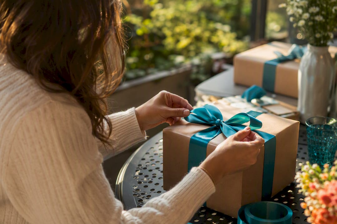 Hands tying decorative bow on gift box