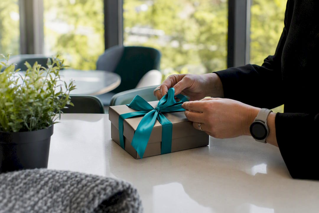 Hands tying teal ribbon on gift box