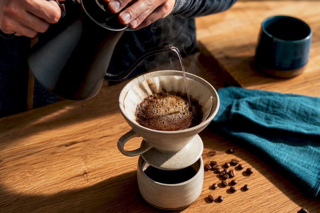 Hands pouring water over ground coffee