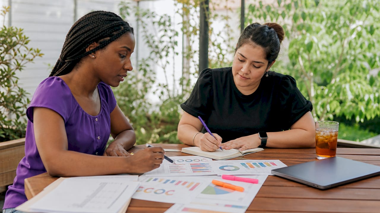 Two women discussing compliance roadmap over documents