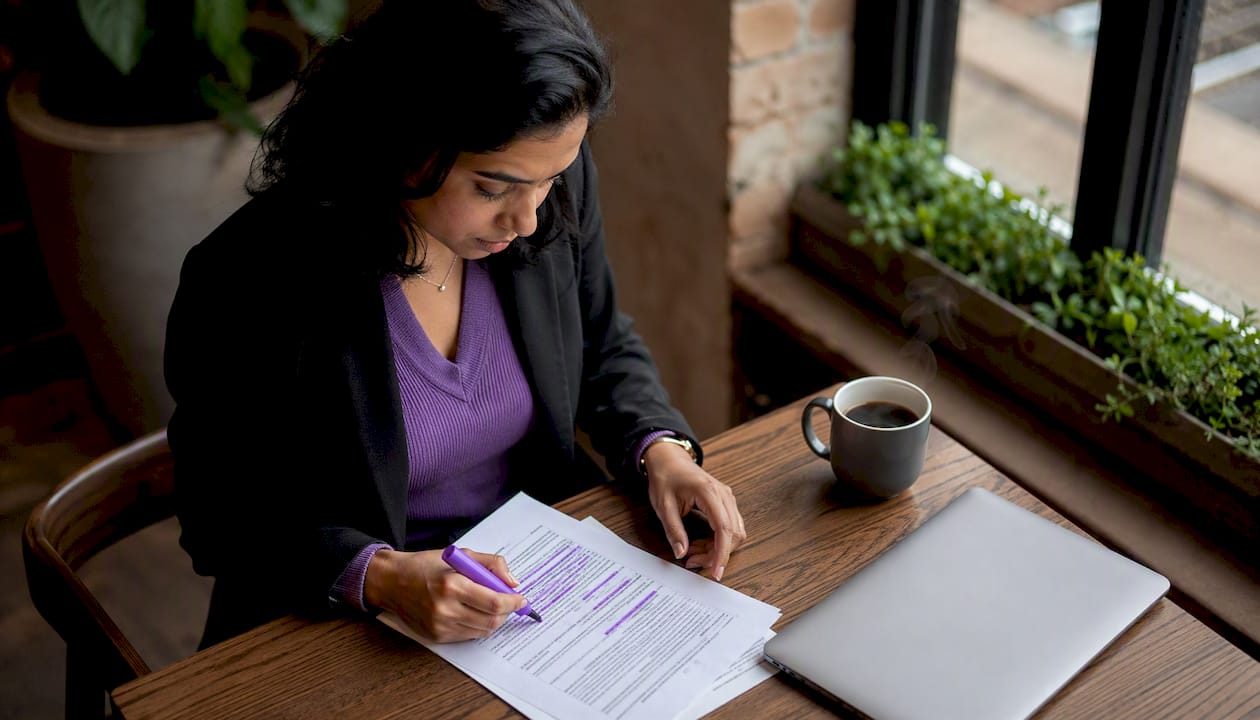 Woman reviewing ISMS policy documents at desk