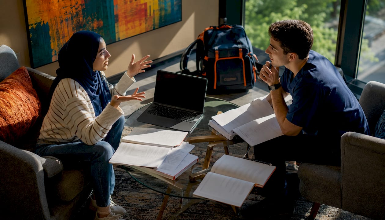 Pair performing peer mock oral exam in library study room