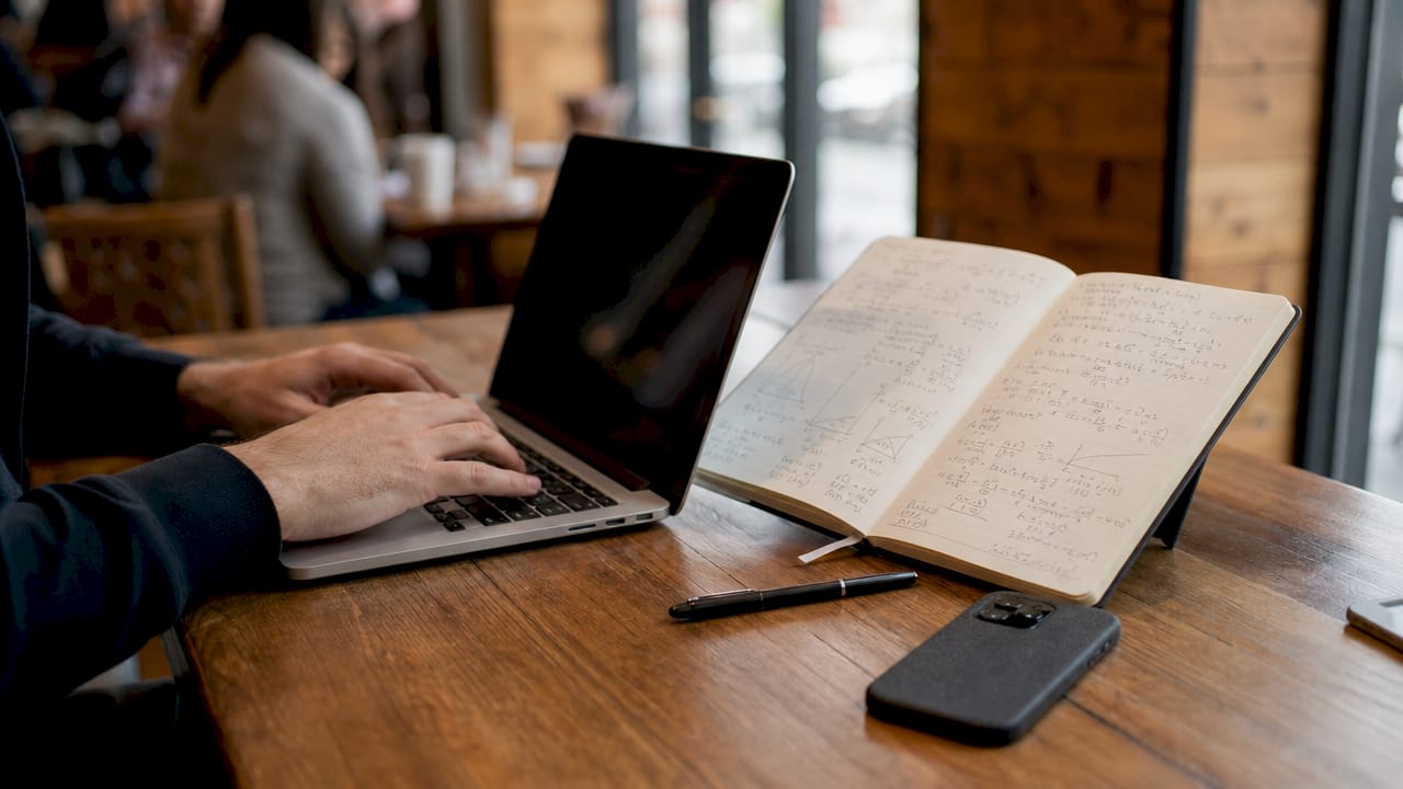Hands typing statistical model equations on laptop