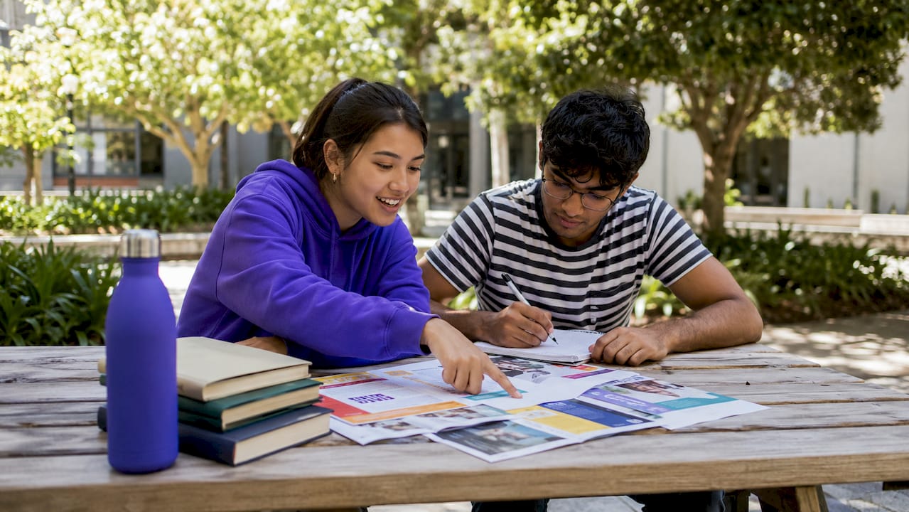 Two students discussing elective courses over coffee