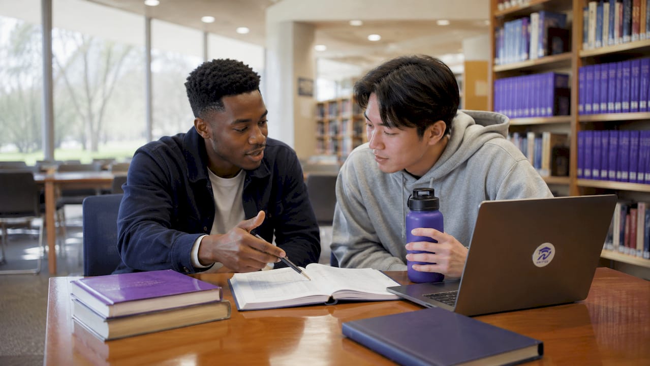 Two students collaboratively reviewing degree map papers