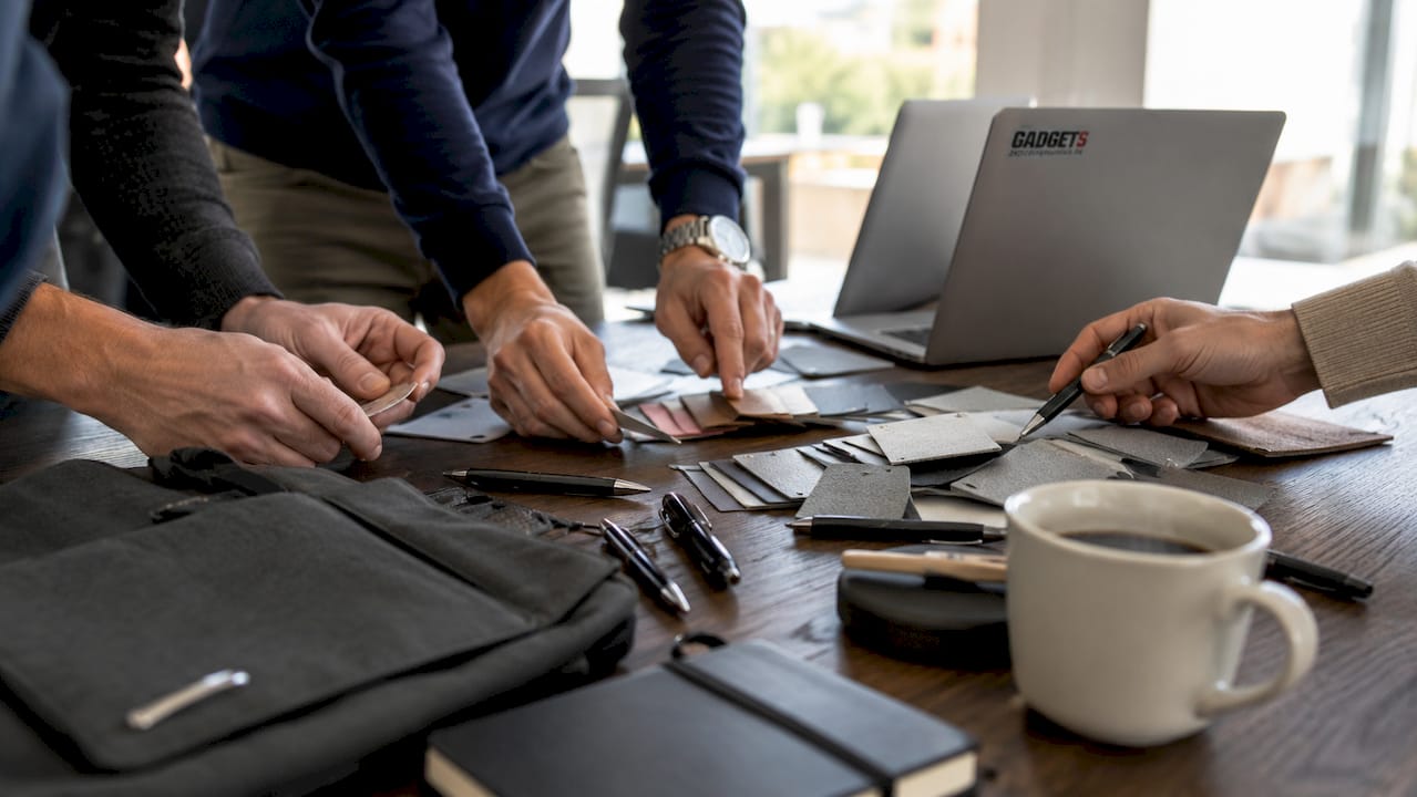Mani che scelgono gadget promozionali personalizzati su una scrivania