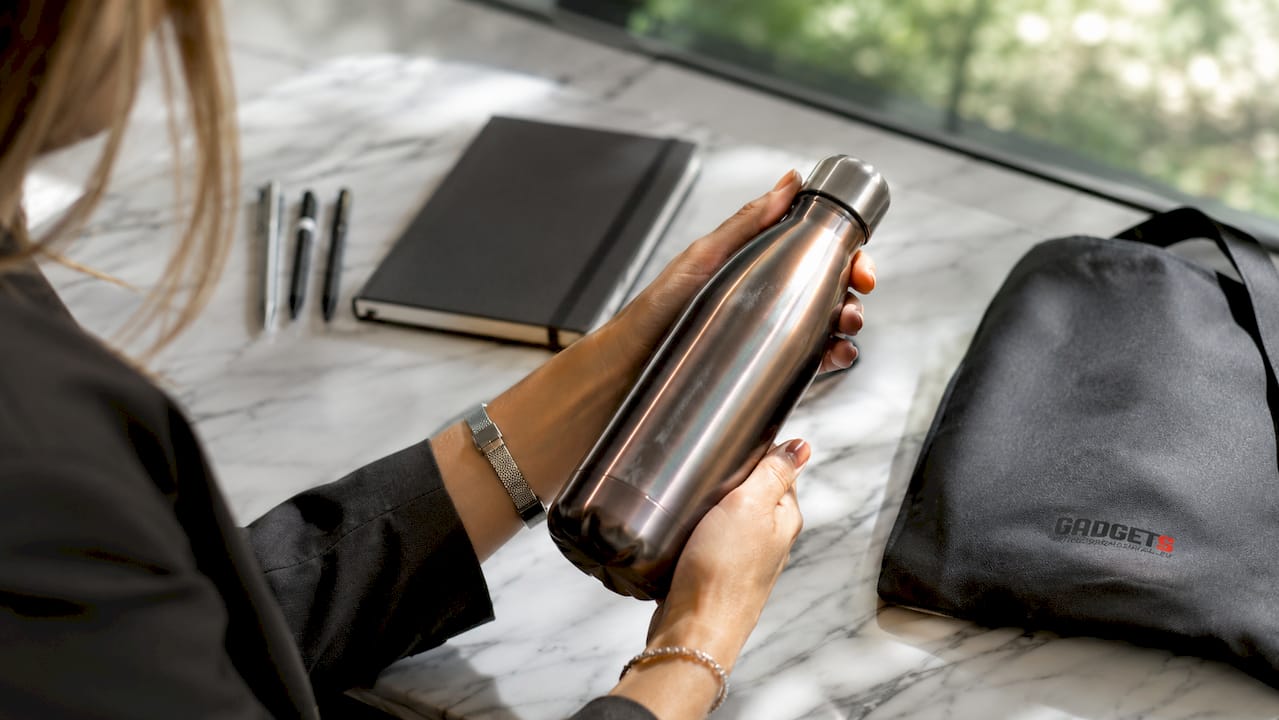 Primo piano di mani che tengono una borraccia e alcuni gadget promozionali