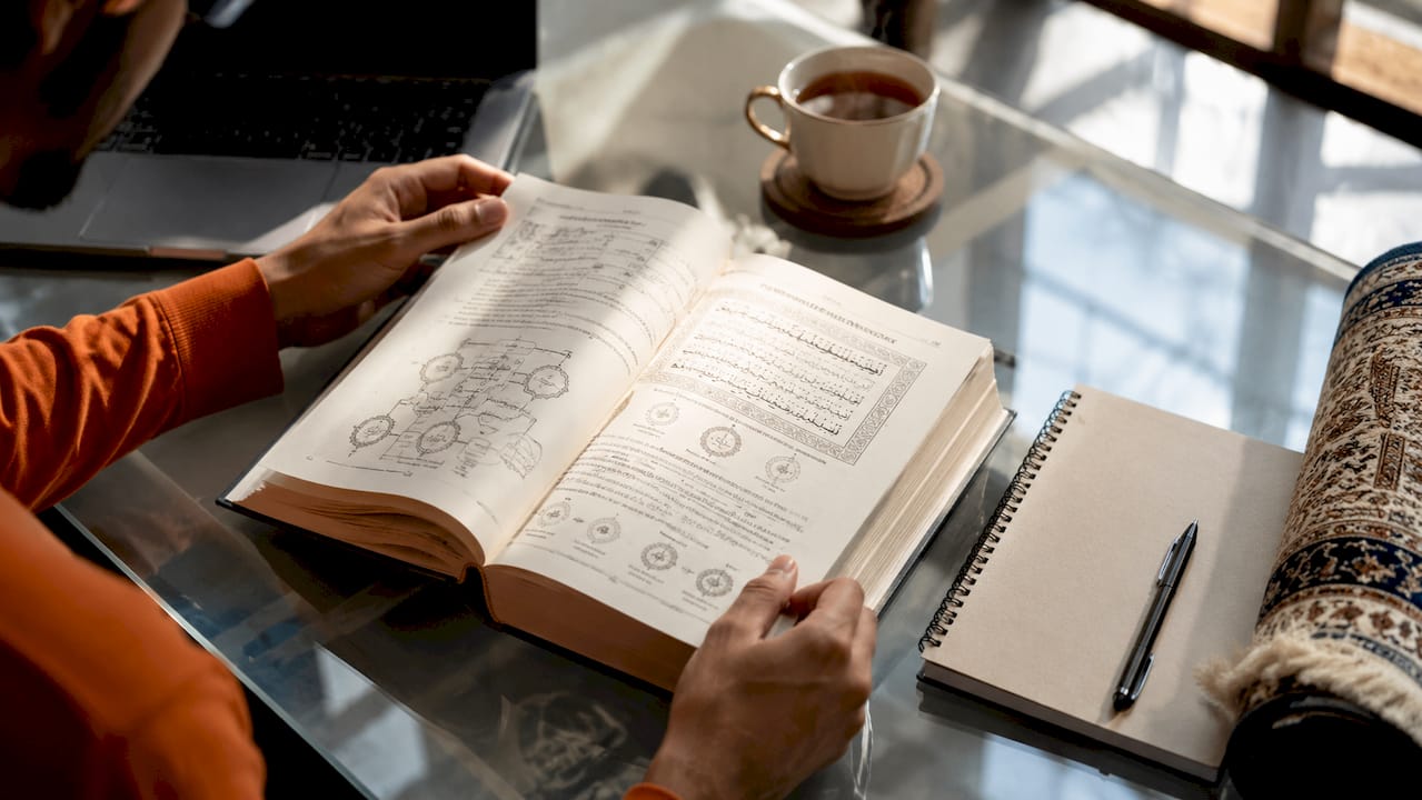 Close-up of hands studying Islamic textbook