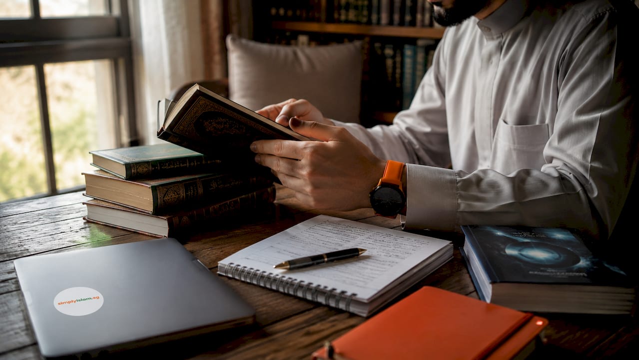 Hands arranging Islamic and science books