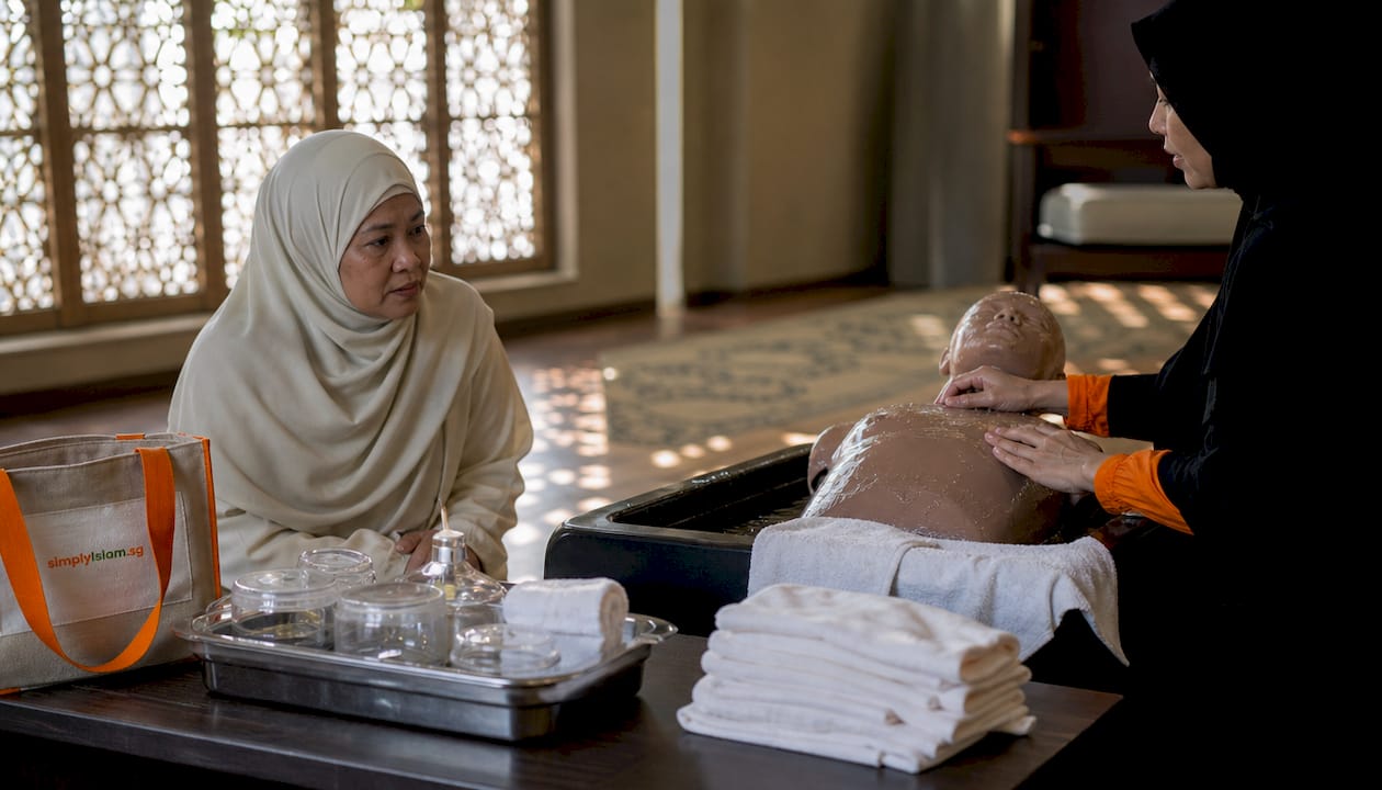 Woman observing ghusl ritual demonstration on mannequin