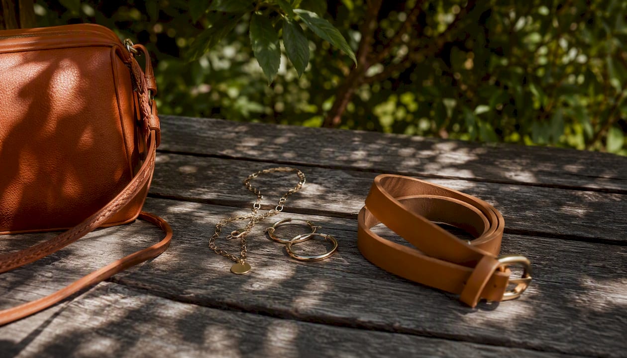 Minimalist leather bag and gold jewelry on wood