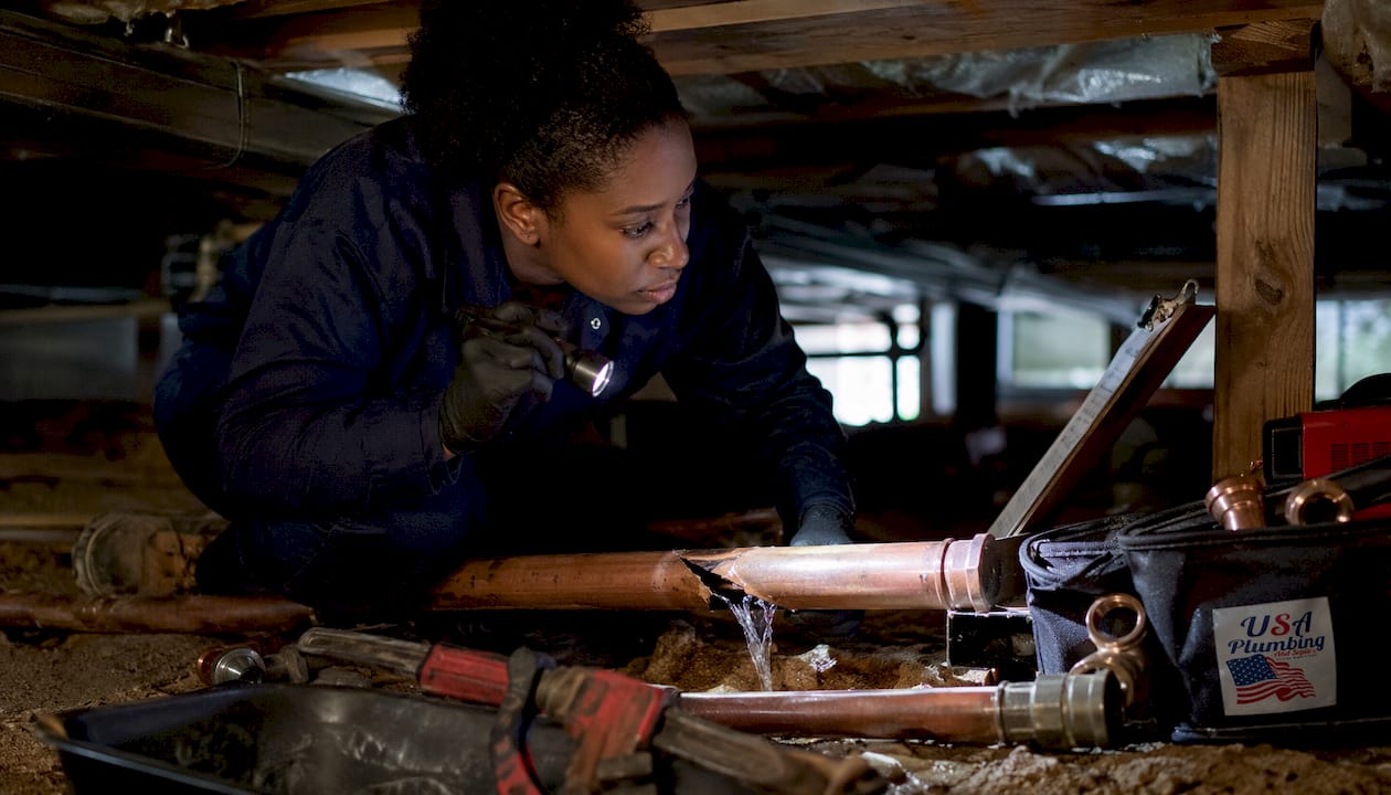 Plumber inspecting burst pipe damage