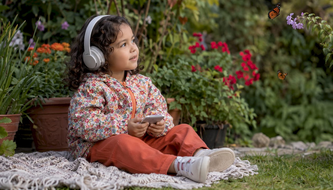 Niño disfrutando de un audiolibro en inglés al aire libre