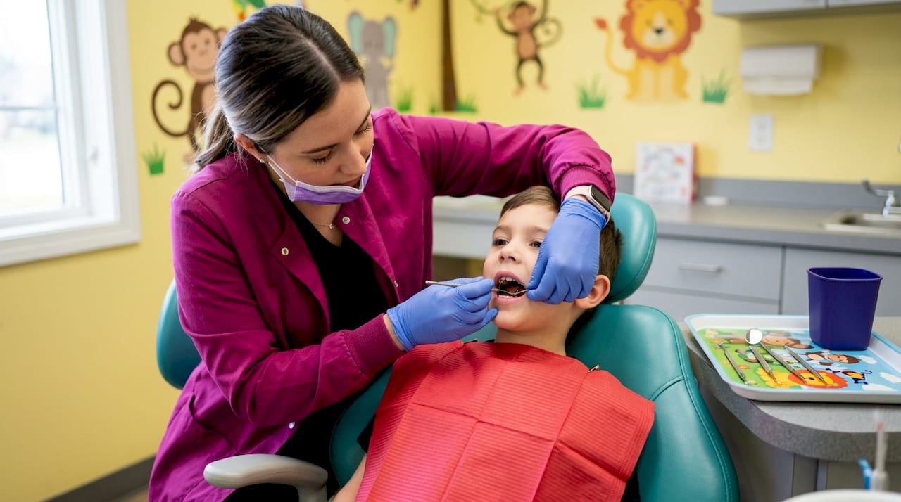 Dentist fitting space maintainer in child’s mouth