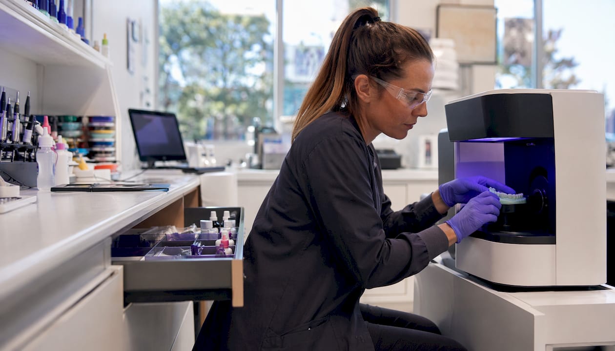 Technician operating digital dental scanner in lab