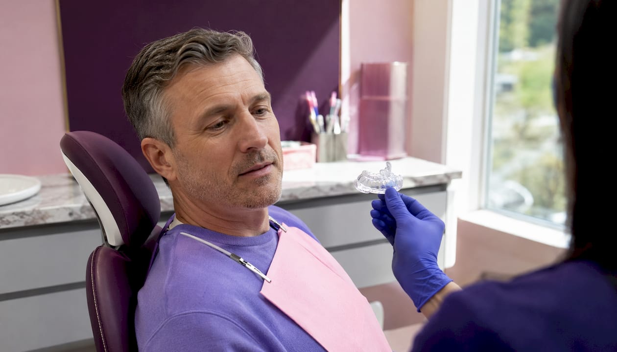 Dentist fitting custom hard acrylic mouth guard
