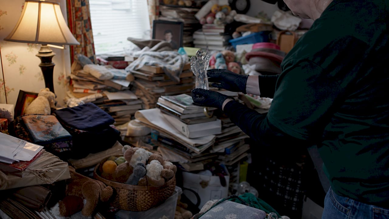 Hands moving fragile item in hoarder estate clutter