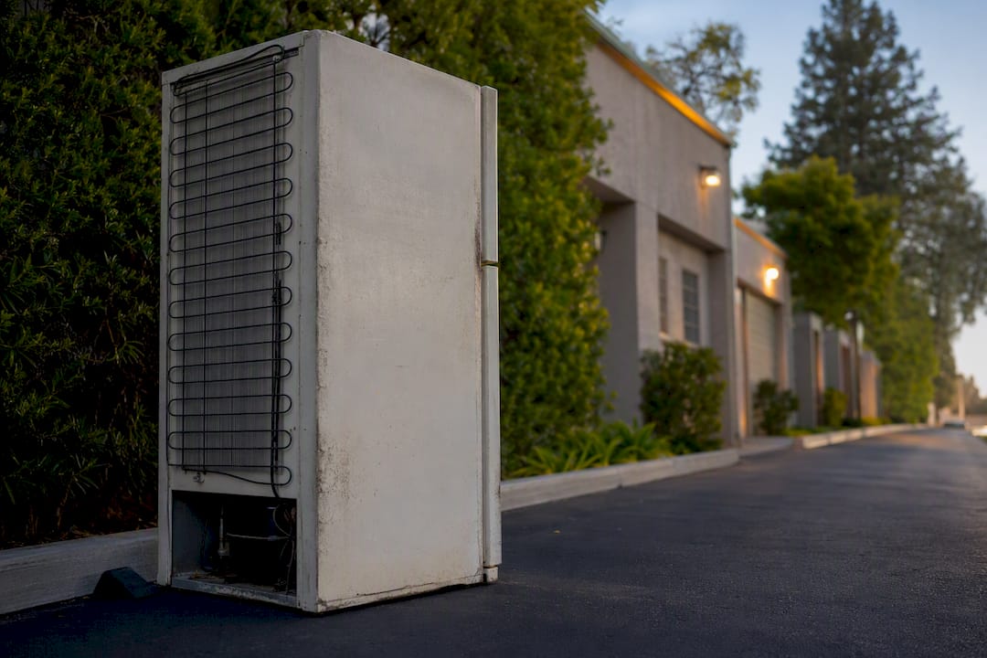 Old refrigerator waiting beside service alley