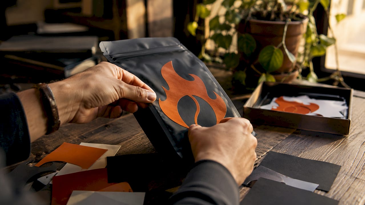 Close-up of hands applying bold typography on coffee bag