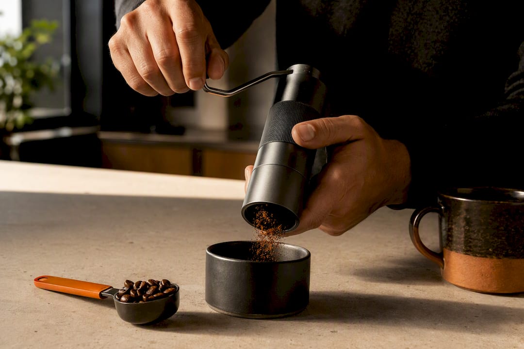 Hands using a manual burr grinder