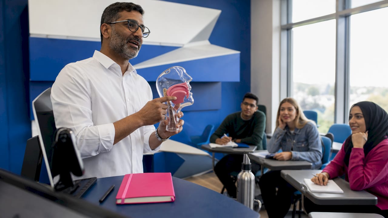 Instructor demonstrating mouth position with phonetics model
