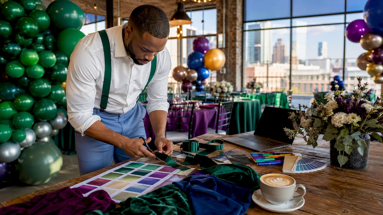 Corporate Holiday Party Decor Ideas for Planners in 2026 Hands cutting green fabric with color swatches