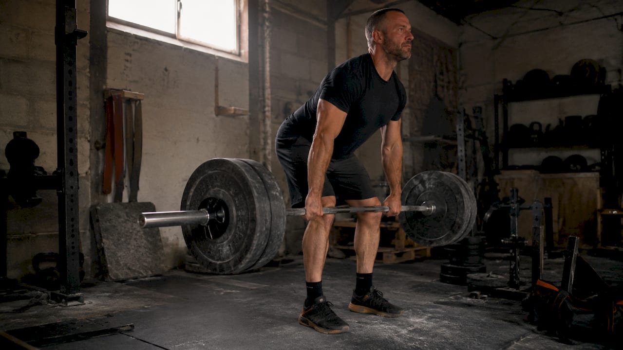 Mid-lift deadlift with barbell demonstrating hip hinge