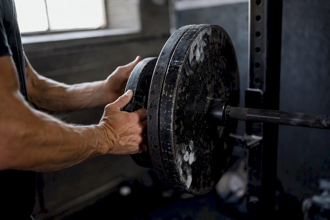 Hands loading plates on barbell