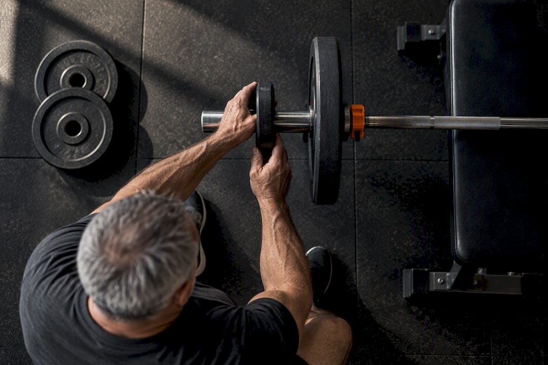 Hands adding a small plate to barbell