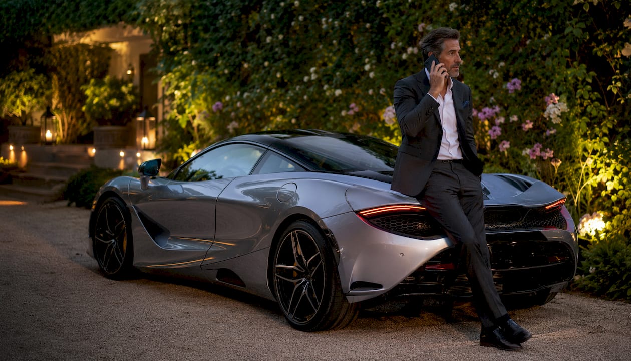 Man beside McLaren 750S on rooftop at dusk