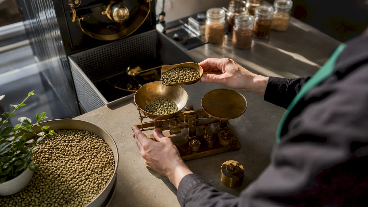 Close-up of hands weighing green coffee beans