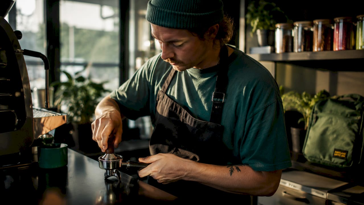 Barista adjusting grinder for fresh coffee brew