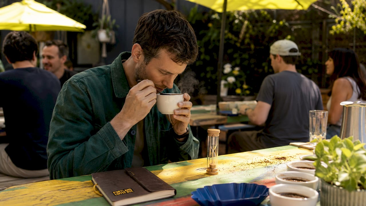 Close-up hands slurping coffee in cupping bowl