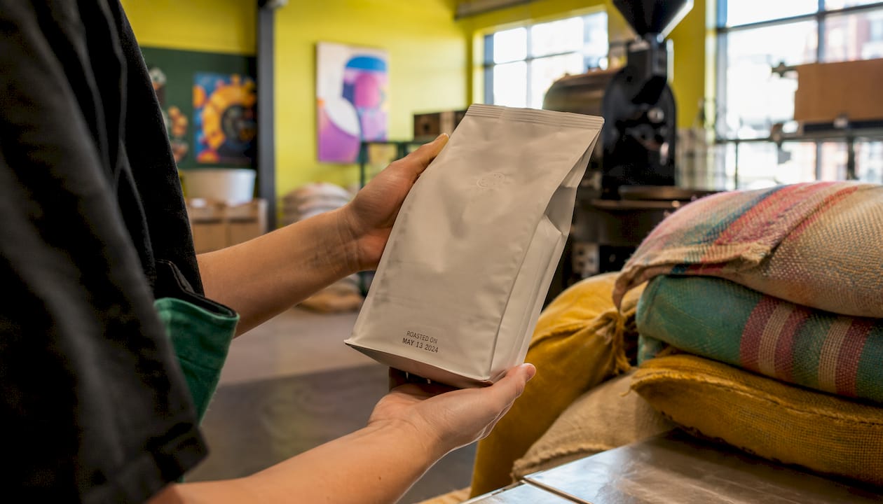 Hands holding coffee bag showing roast date stamp