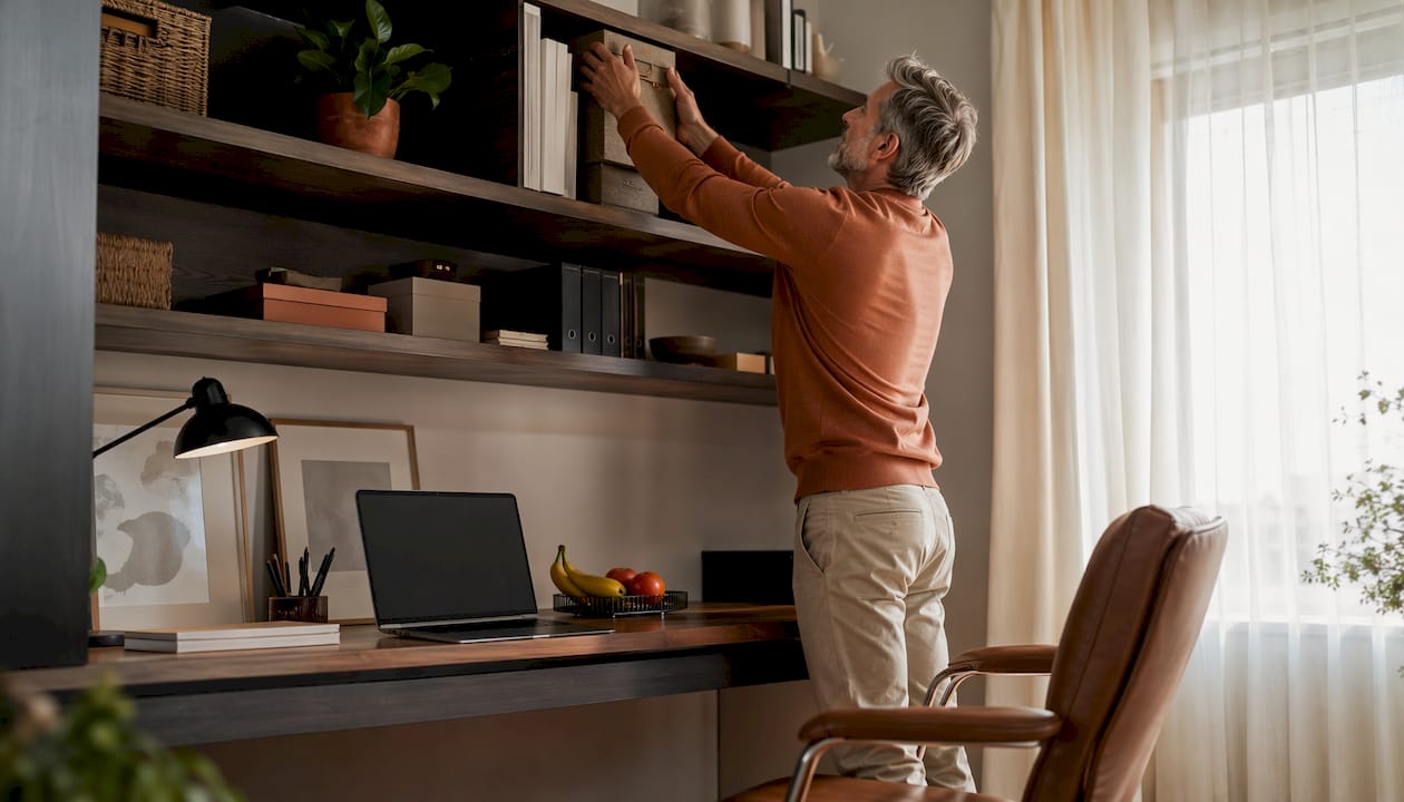 Man adjusting vertical shelving in small office