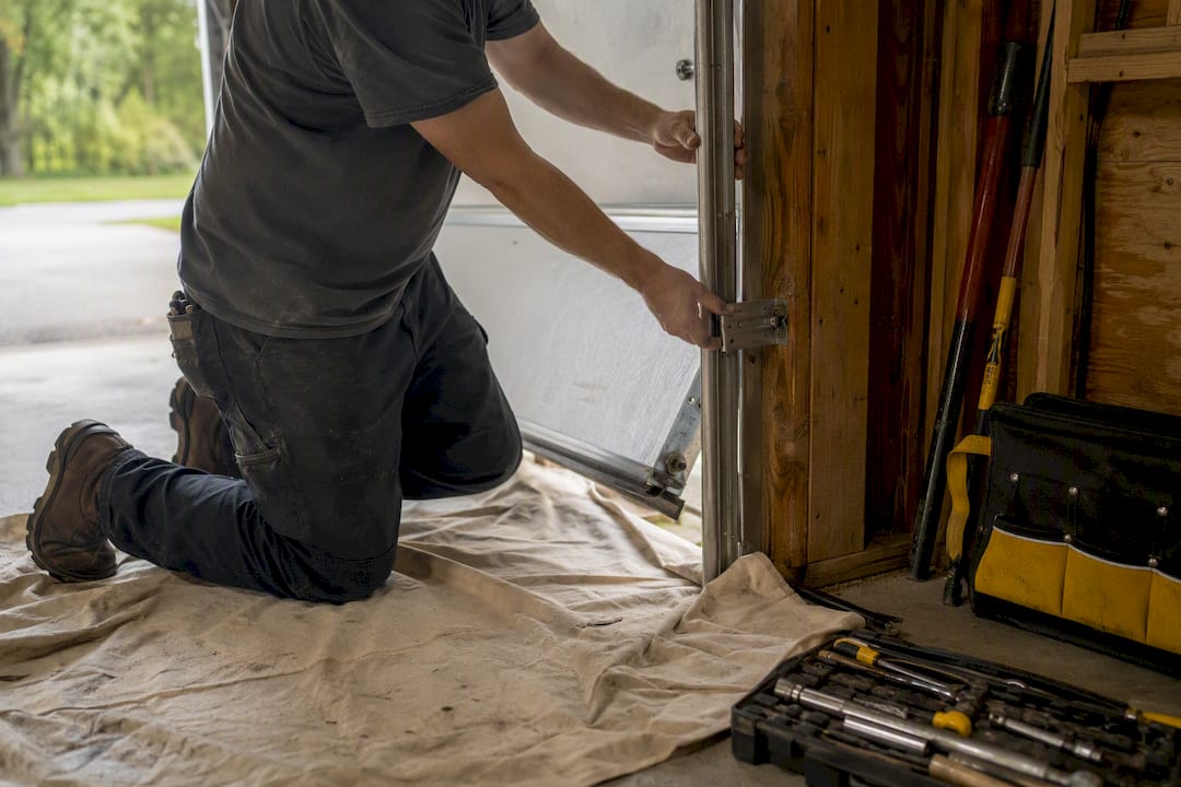 Hands realigning off-track garage door roller and hinge