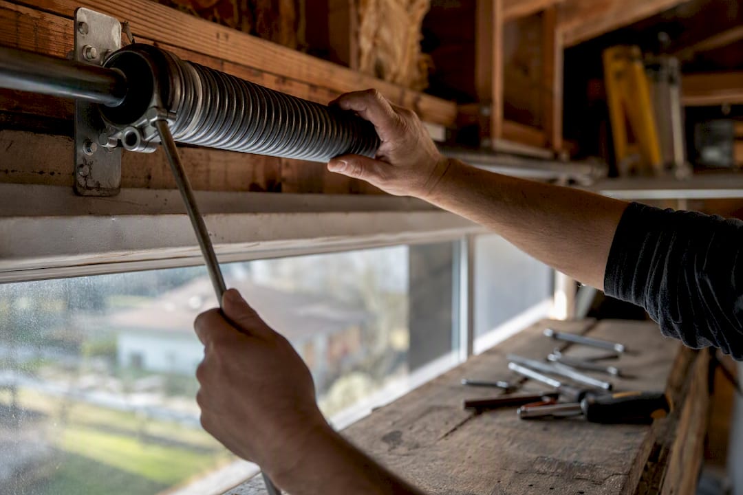 Close-up of hands repairing garage torsion spring