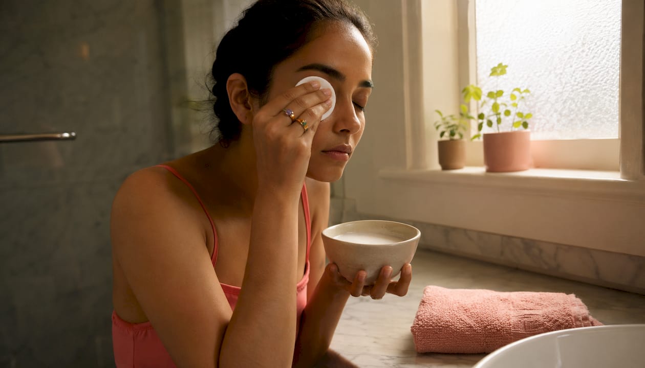 Hands removing waterproof mascara with cotton pad