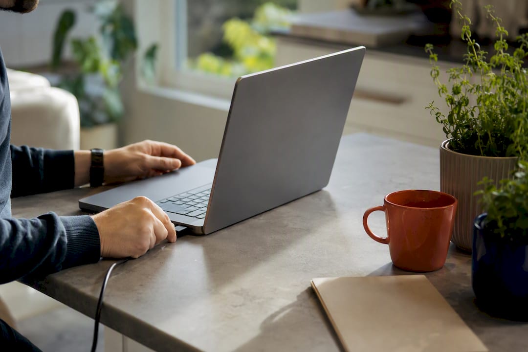 Hands connecting power cable to laptop