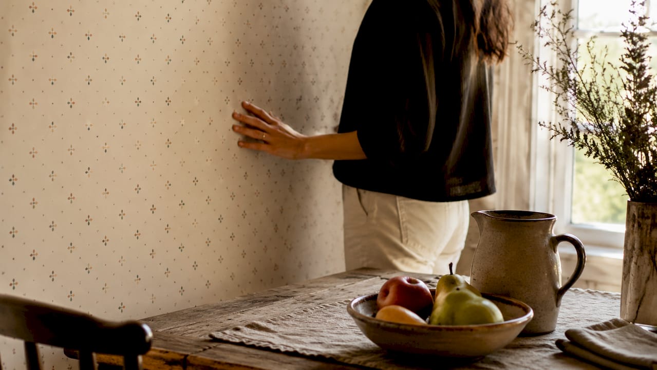 Hand touching small-scale floral wallpaper texture