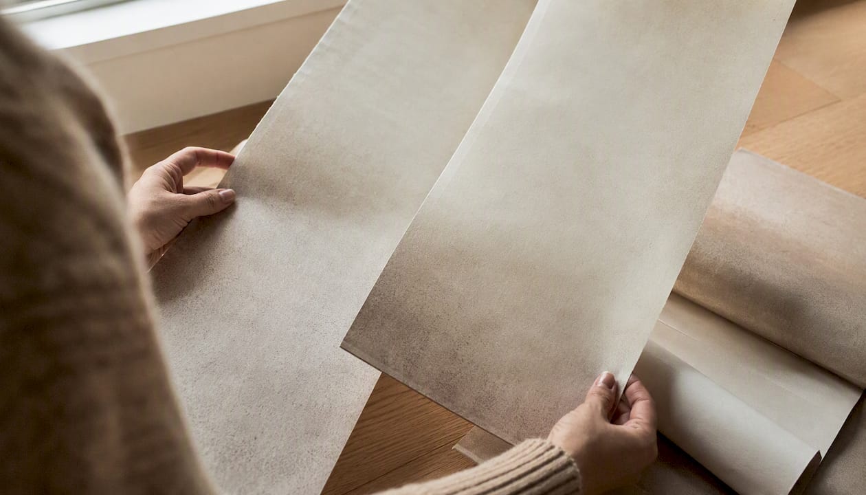 Hands preparing reverse-hanging wallpaper strips