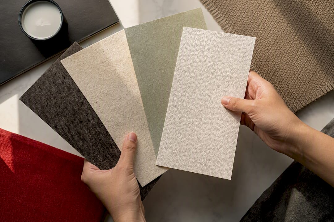 Hands comparing wallpaper substrate swatches